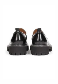 Black leather shoes with a glossy finish, featuring a thick, rugged black sole, rear pull tab, and contrasting white stitching.