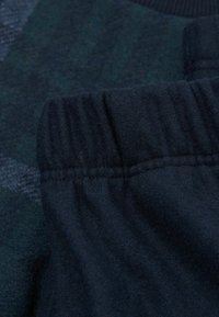 Donkerblauwe stof met een zachte, textuur. Heeft een geribde elastische tailleband met verstevigde stiksels. Geschikt voor casual dragen.
