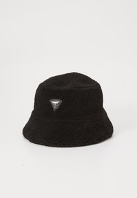 Cappello a secchiello nero realizzato in pile testurizzato con una toppa a forma di triangolo sulla parte anteriore. Parte superiore morbida e arrotondata e ampia visiera flessibile.