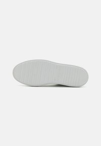 White rubber shoe sole with horizontal grooves and branded text. Smooth texture with a rounded toe and flat heel.