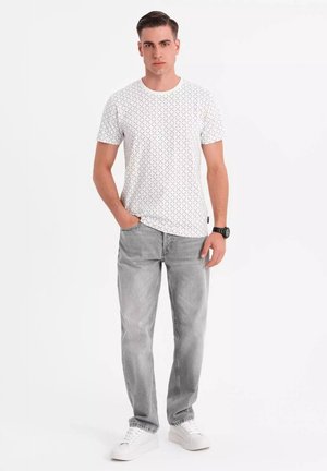 Hvid kortærmet skjorte med et geometrisk mønster, parret med lysegrå jeans og hvide sneakers. Outfittet har en afslappet pasform.