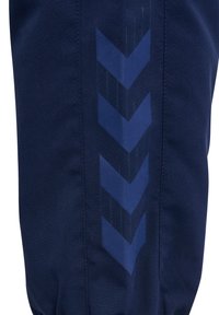 Ciemnoniebieska tkanina z pionowym wzorem czterech ciemnych strzałek w kształcie szewronów wskazujących w dół wzdłuż przeszycia.