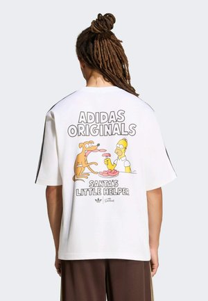Persona con rastas lleva una camiseta blanca de Adidas Originals con los personajes de Los Simpson, Homer y el perro Santa's Little Helper, compartiendo salchichas.