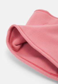 Chapeau en polaire rose avec une texture douce, une forme arrondie et des bords cousus. L'intérieur est confortable, mettant en valeur des couches de tissu lisse.