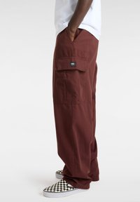 Bordeaux cargobroek met een relaxed fit, zijzakken en een geweven label op de achterzak. Gecombineerd met zwart-wit geruite instapschoenen.