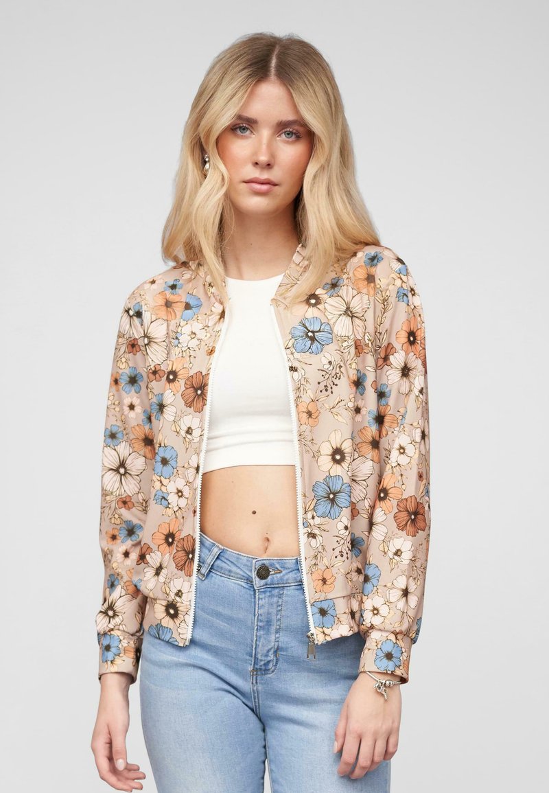Veste bomber florale en pêche clair avec des fleurs bleues et oranges. Dotée d'une fermeture éclair à l'avant, de poignets élastiques et d'une coupe décontractée. Assortie avec un jean clair.