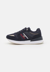 Navy blue sneakers with suede and textile upper, featuring gold accents, white and red stripes, and a white rubber sole with textured pattern.