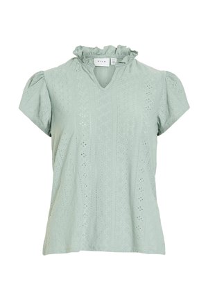 Blouse vert clair à manches courtes avec col à volants et motif en dentelle ajourée, décolleté en V et manches légèrement bouffantes.