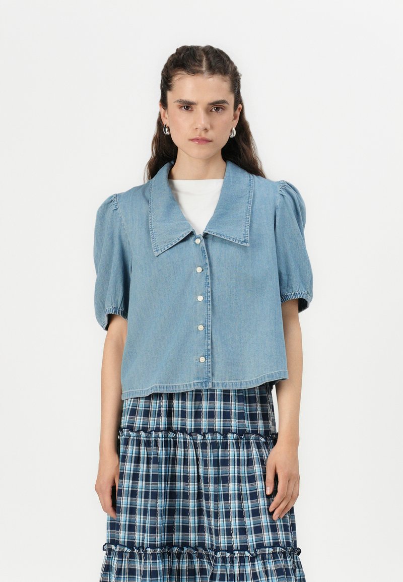 Lichtblauwe denim cropped jas met een grote kraag en pofmouwen, voorzien van een knoopsluiting aan de voorkant en een gladde textuur.