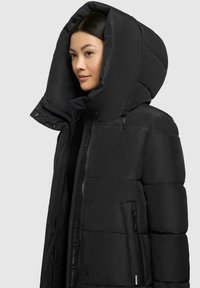 Schwarze Daunenjacke mit großer Kapuze, gestepptem Material, Frontreißverschluss und Seitentasche. Hergestellt aus leichtem, isolierendem Material.