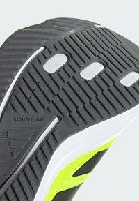 Black and grey textured shoe sole with a prominent ADIWEAR logo. Features a vibrant lime green accent and patterned traction surface.