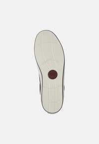 Semelle de chaussure en caoutchouc blanc texturé avec un motif de bande de roulement ; présente un logo circulaire marron au centre. Bords arrondis et légère élévation du talon.