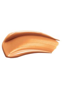 Échantillon de fond de teint crémeux dans une teinte orange-brun chaud, texture lisse, finition légèrement réfléchissante, appliqué en forme courbée sur un fond blanc.