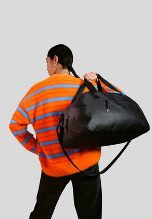 Borsone nero con texture lucida, chiusura zip e doppie maniglie. Il borsone presenta una tracolla rimovibile e accessori in contrasto.