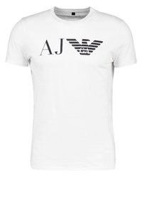 Vit bomullströja med svarta texter "AJ" och "GA" samt en stiliserad örnlogotyp, korta ärmar och rundad halsringning.