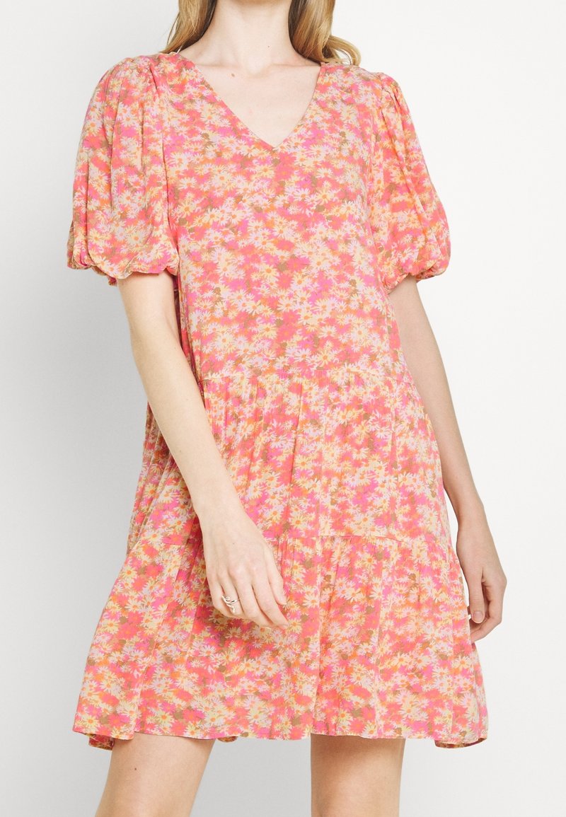 Blumenkleid in Pink- und Orangetönen mit Puffärmeln, V-Ausschnitt, gestuftem Rock und leichtem Stoff, der kleine Gänseblümchenmuster aufweist.