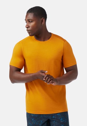 T-shirt a maniche corte con collo rotondo di un vivace arancione, realizzato in tessuto testurizzato. Presenta un design aderente e dettagli senza cuciture sulle spalle.