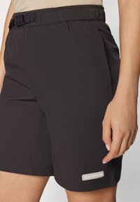 Black athletic shorts made of lightweight fabric, featuring an adjustable waistband with belt, and a logo detail on the lower left side.