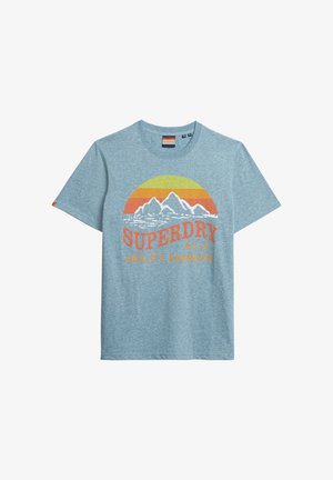 Lichtblauw katoenen T-shirt met een grafisch ontwerp van bergen en een zon in oranje en geel, met de tekst "SUPERDRY MFG CO QUALITY GARMENTS" in vetgedrukt.