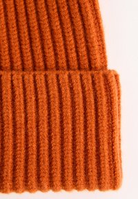 Bonnet en tricot orange avec une texture côtelée verticale et un revers replié, fabriqué à partir d'un fil doux et duveteux.