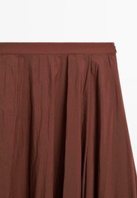 Gonna marrone plissettata con una vita liscia e chiusura con zip, realizzata in un tessuto leggero e testurizzato con un aspetto rugoso.