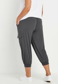 Grijze, relaxed fit cargobroek met taps toelopende enkels, zijzakken en een elastische tailleband. Gecombineerd met witte sneakers. Zachte stofstructuur.