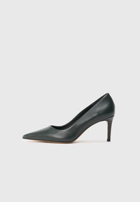 Décolleté in pelle verde con tacco alto, punta affusolata, texture liscia e tacco sottile. Il design presenta una silhouette classica e un branding discreto.