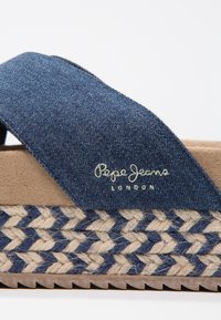 Blå denim slide sandal med tan mikrofiber fotbädd, vävd jute-detalj vid basen och präglad "Pepe Jeans London"-logotyp.