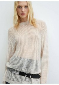 Kevyt, neulepaita vaaleassa sävyssä, jossa on raidallinen kuvio. Ominaisuuksiin kuuluu löysä istuvuus ja laskettu olkapää. Yhdistetty mustalla niittivyöllä.