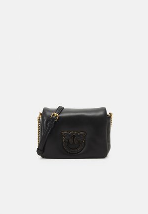 Borsa a tracolla in pelle nera con design a faccina sorridente, dettagli dorati e una catena come tracolla. Presenta una texture liscia e una forma arrotondata.