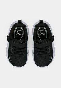 Baskets de sport noires en mesh avec des accents blancs, dotées de lacets et d'une sangle pour un maintien sûr. Conçues pour le confort avec une surface texturée.