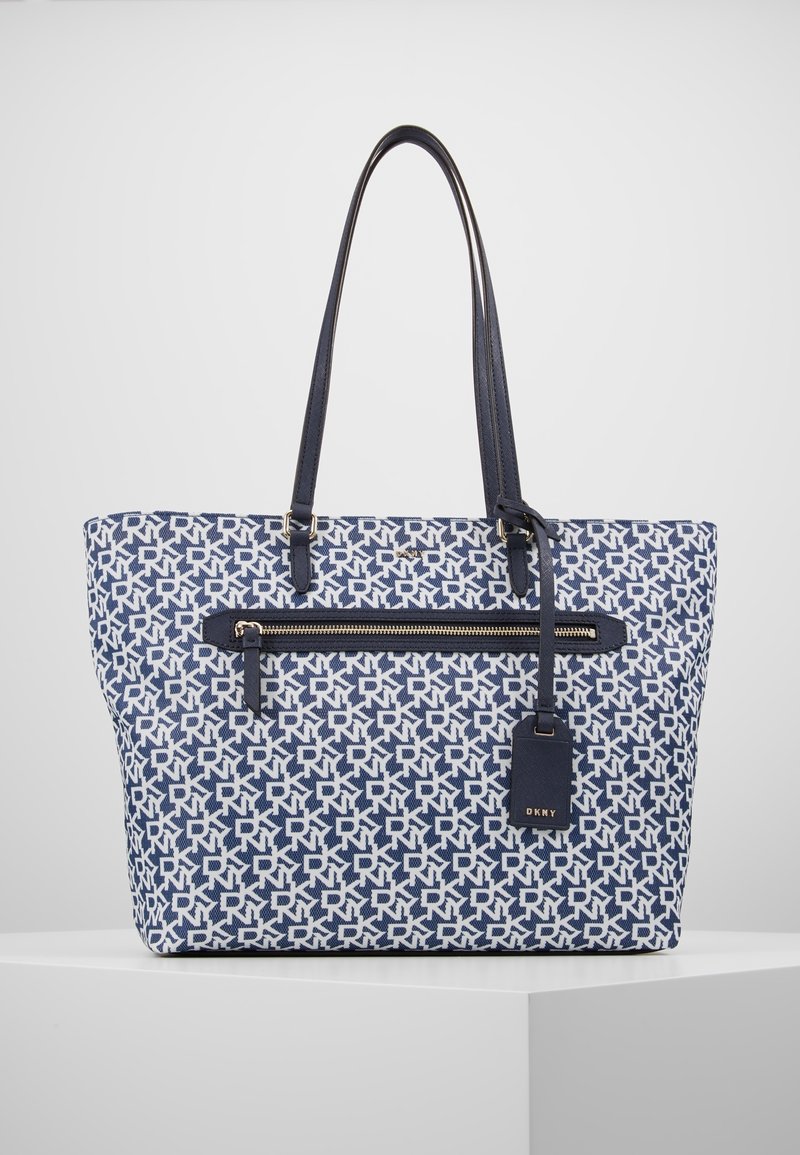 Plátěná taška přes rameno v námořnické modři a bílé barvě s geometrickým vzorem, přední kapsa na zip, dvěmi popruhy a koženou značkovou cedulkou.