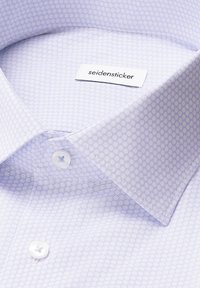 Colletto di camicia viola chiaro con motivo a pois, dotato di un'etichetta bianca con la scritta "seidensticker" e bottoni bianchi. Tessuto di consistenza liscia.