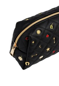 Bolso negro de cuero acolchado con cremallera dorada, decorado con pequeños símbolos bordados como sol, luna, flores, flechas y corazones.