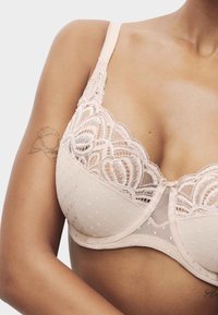 Lyserød blush blonde-bh med prikket mønster, gennemsigtige bægre og blomsterblonde detaljer på kanterne. Justerbare stropper og en lille sløjfe i midten.