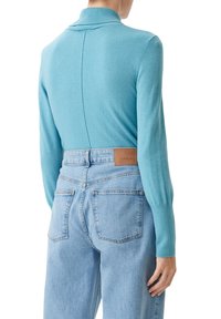 Maglione fitted azzurro chiaro con colletto a coste, maniche lunghe e texture liscia, abbinato a jeans in denim chiaro a vita alta con etichetta.