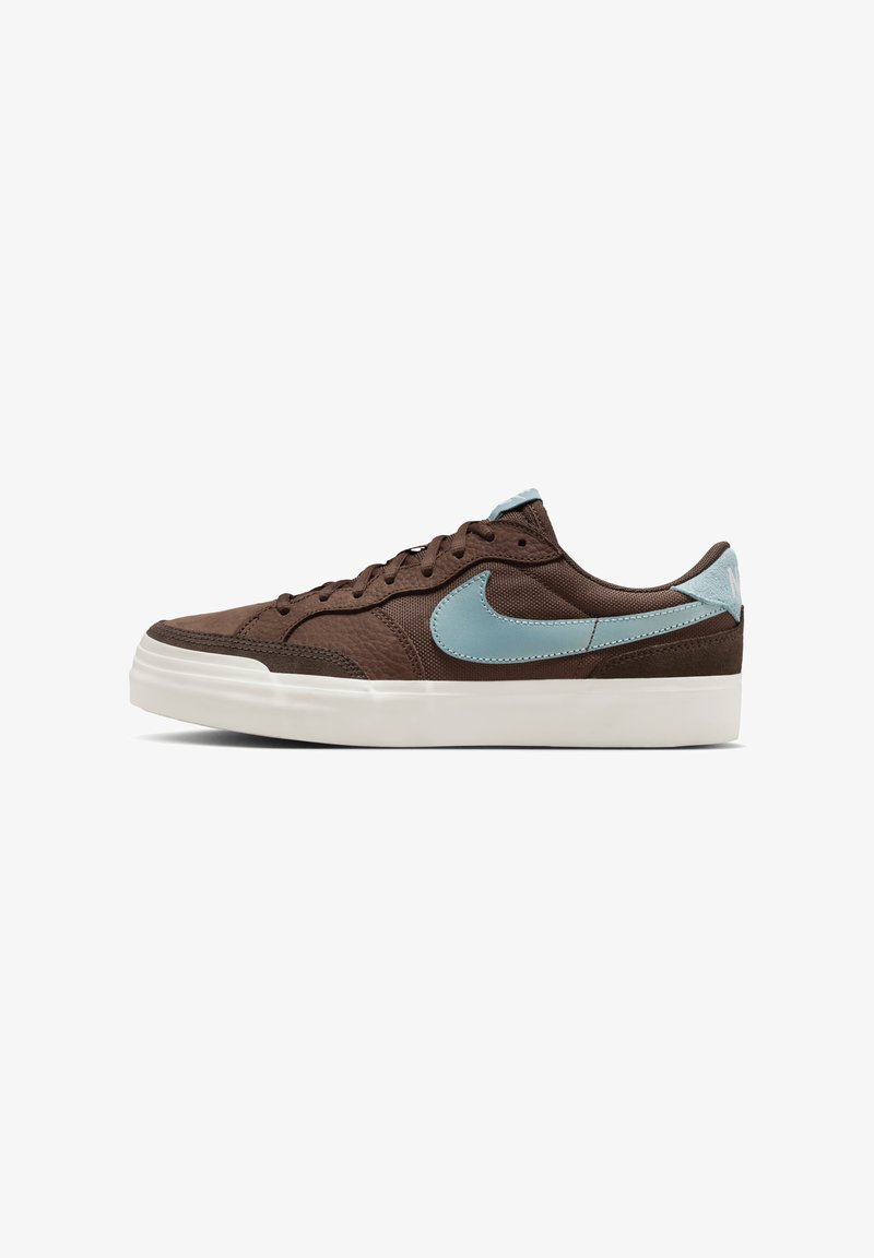 Brūni sporta apavi ar teksturētu materiālu, gaiši ziliem akcentiem un baltu gumijas zoli. Iezīmējas ar apaļu purngalu un plakaniem šņorīšu. Sānu swoosh dizains.