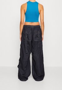 Blue ribbed crop top paired with black baggy cargo pants featuring large pockets and loops, with a relaxed fit and soft texture.