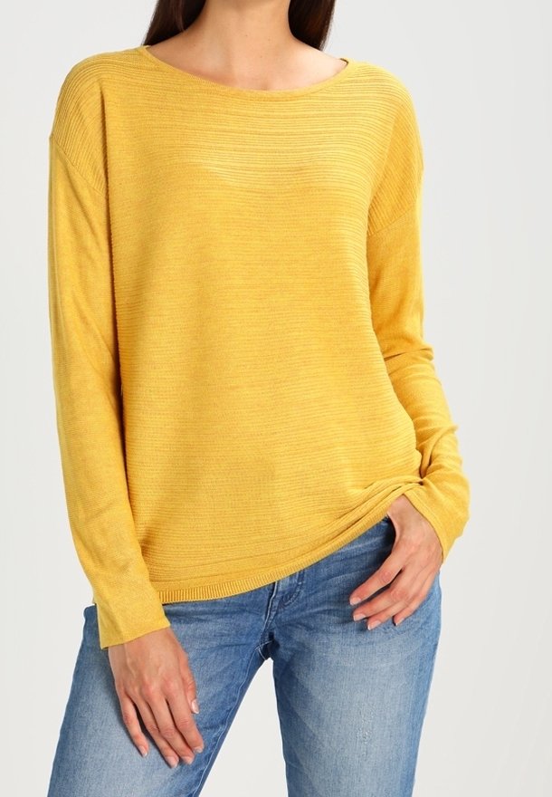 Gelber Langarm-Pullover mit gerippter Textur und weitem Ausschnitt, kombiniert mit hellblauen Jeans. Der Schnitt ist lässig.