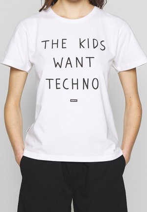 Biała koszulka bawełniana z czarnym napisem "DZIECI CHCĄ TECHNO". Koszulka ma okrągły dekolt i krótkie rękawy, a z boku znajduje się mała etykieta z logo.