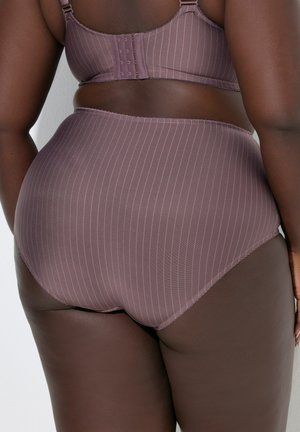 Persona dalla pelle scura che indossa biancheria intima mauve a righe sottili, a vita alta, e un reggiseno abbinato, vista da dietro contro una parete semplice.