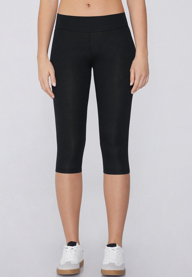 Leggings capri noirs en tissu lisse et léger. Comprend une taille haute élastique, une coupe ajustée et sans motifs ou accents visibles.