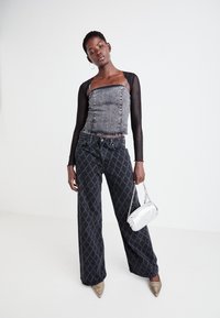 Črn denim kratek top s srebrnim šivanjem; hlače širokega kroja z vzorcem v črni barvi in belimi diamanti; srebrna torbica; bež špičaste čevlje.