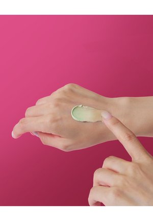 Trois pots de crème Dr. Jart+ Cicapair de tailles variées, avec un emballage vert et blanc. Un échantillon de produit vert clair est à côté d'eux.