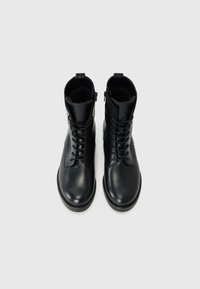 Zwarte leren enkelboots met een gladde textuur, veter sluiting aan de voorkant en ritssluiting. Zachte voering en rond neu ontwer.