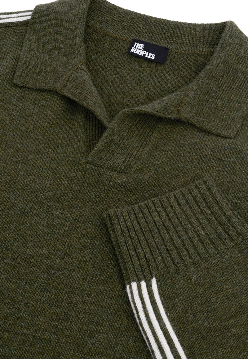 Pull en tricot vert olive avec col, poignets côtelés arborant trois rayures blanches et une étiquette noire portant la mention "THE KOOPLES."