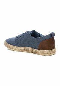 Zapato de lona azul con acento de cuero marrón, suela de yute trenzado estilo espadrille, puntera redonda, cinco ojetes y diseño de corte bajo.