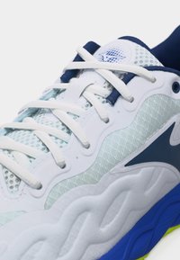 Λευκό και μπλε αθλητικό παπούτσι με δίχτυ, λευκά κορδόνια, ανατομική σόλα και λογότυπο στη γλώσσα.