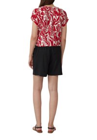 Top a maniche corte a righe rosse e bianche abbinato a pantaloni corti neri. La maglietta presenta un motivo a foglia, mentre i pantaloni hanno una vestibilità comoda.