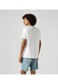 White cotton t-shirt with short sleeves, round neckline, paired with light blue denim shorts featuring frayed hems and back pockets.